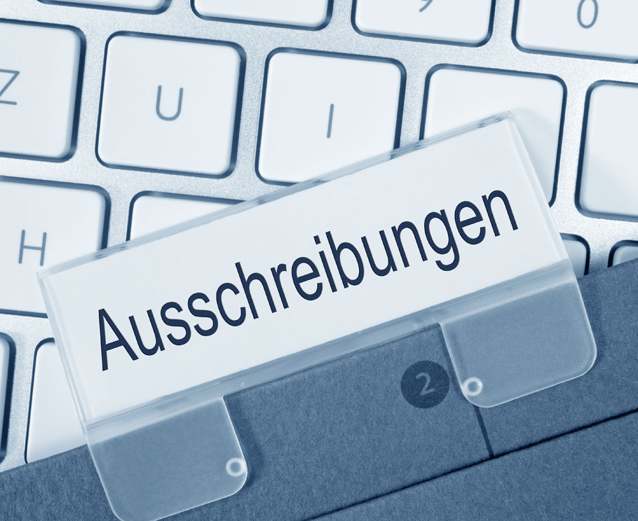 Ein Ordner mit dem Reiter Ausschreibungen liegt über einer Tastatur
